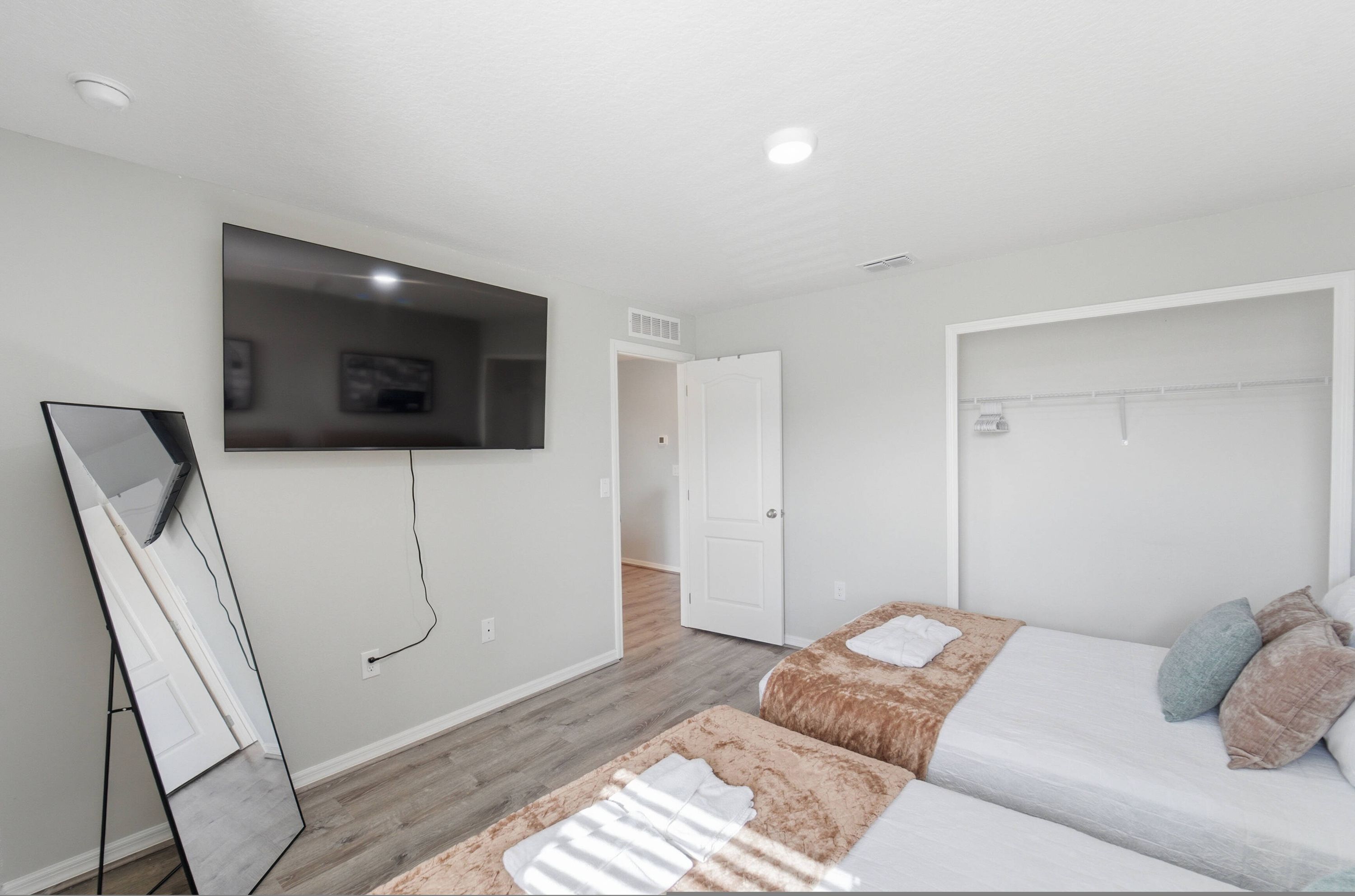 Una camera d'albergo con un letto, una TV a muro, uno specchio e un armadio.