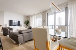 Ein modernes Wohnzimmer mit einer Couch, einem Glastisch und einem Flachbildfernseher.