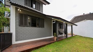 Ein zweistöckiges Haus mit überdachter Veranda, einem kleinen Garten und einer sichtbaren Außeneinheit der Klimaanlage.