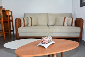 A modern living room with a beige sofa, a wooden coffee table, and a patterned ball on the table. - Casa na Praia dos Ingleses -NIN019 (Florianópolis)
