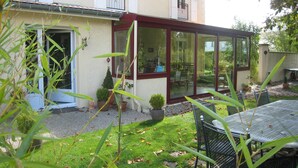 A house with a covered patio, a small garden, and outdoor furniture. - Guest Room "Les Charmilles - Beige Room" (Charny-sur-Meuse)