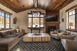 Una sala de estar con chimenea, techo de madera y ventanas amplias.