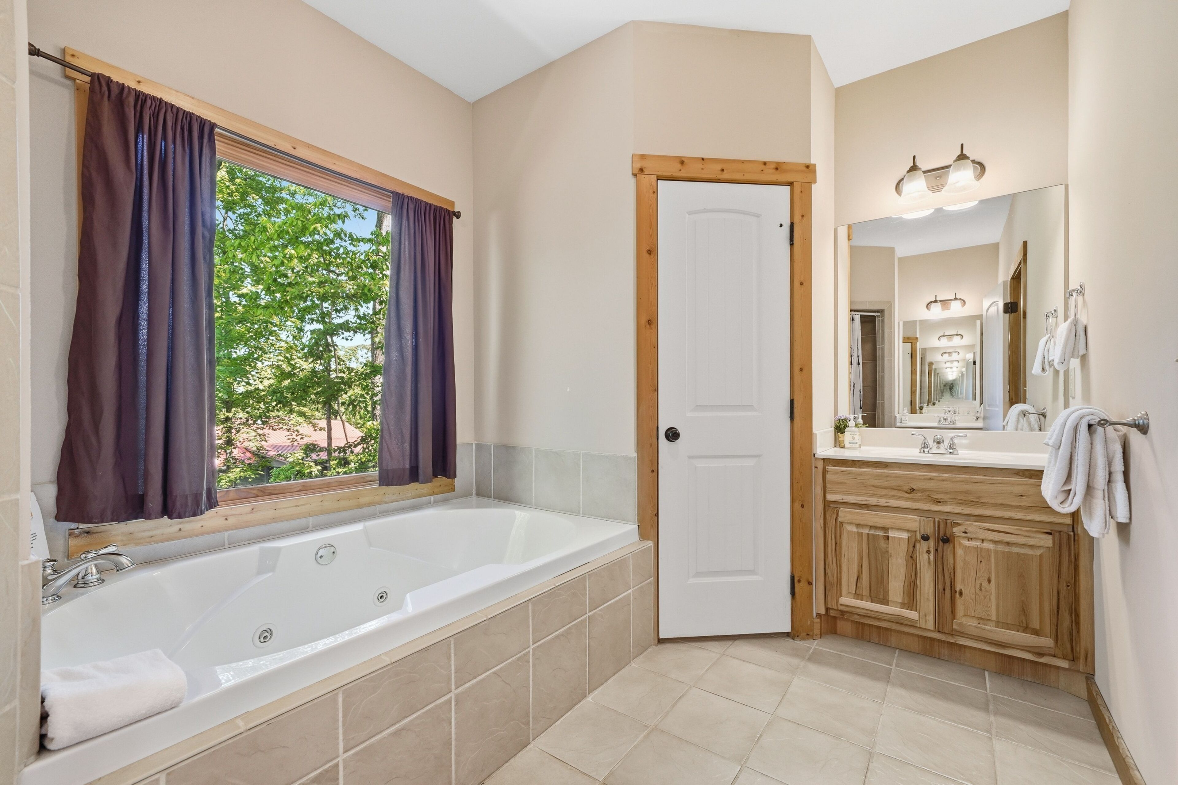 A bathroom with a bathtub, a sink, a mirror, and a door.