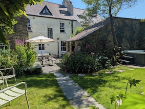 A stone building with a garden patio, outdoor seating, and a hot tub. - The Secret Garden (Narberth)