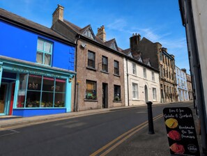 A street with buildings, including a blue storefront with a sign reading 'PLUMVANILLA CAFE'. - The Secret Garden (Narberth)