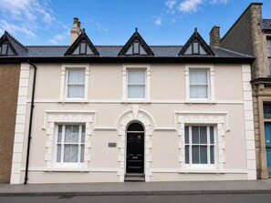 A two-story building with a symmetrical facade, a central entrance with a black door, and a pitched roof with dormer windows. - The Secret Garden (Narberth)