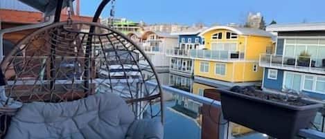A balcony with a hanging chair, a view of colorful buildings, and a clear sky.