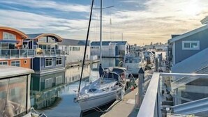 A marina with boats docked, a building with a balcony, and a clear sky.
