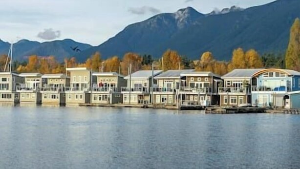 A waterfront hotel with multiple buildings, a dock, and mountains in the background.
