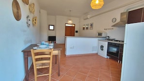 A compact kitchen with a dining area, a washing machine, and a built-in oven. - Podere 23 - Two Bedroom Apartment, Sleeps 5 (Alghero)