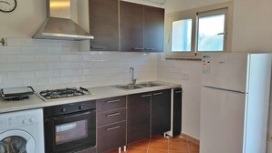 Cocina compacta con estufa a gas, horno, fregadero y refrigerador.