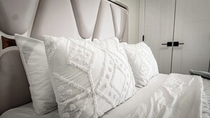 A bed with white bedding and decorative pillows, a headboard, and a wardrobe in the background. - Luxury Comfort Stay in Keswick | 2Bedrooms- 1Bath (Edmonton)