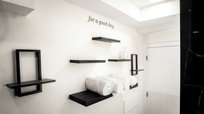 A modern bathroom with white walls, black floating shelves, and a towel on one of the shelves. - Luxury Comfort Stay in Keswick | 2Bedrooms- 1Bath (Edmonton)