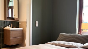 Une chambre à coucher avec un lit, une commode en bois, un miroir et une fenêtre.