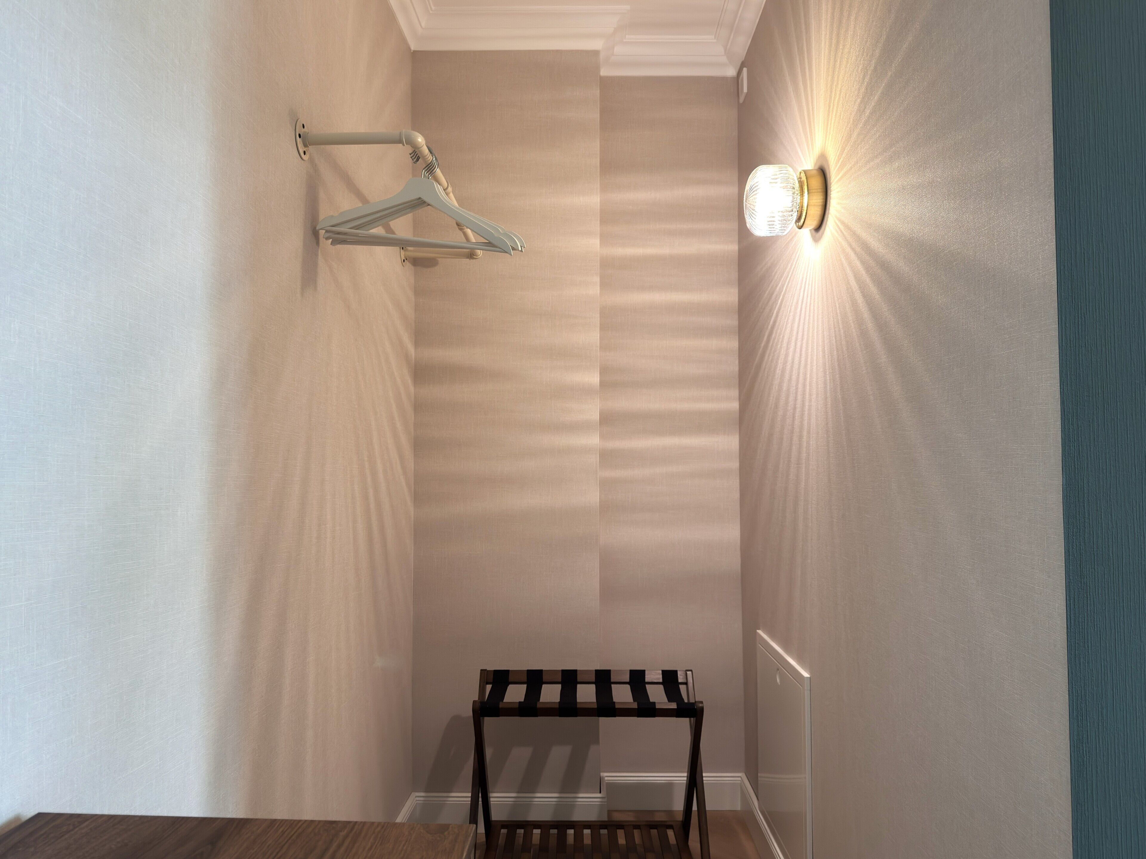 Un pasillo con un perchero, una lámpara de pared y una pequeña mesa.