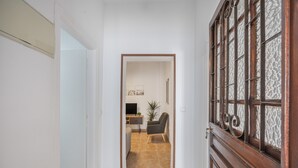 Un pasillo con una puerta de madera, un escritorio con una silla y una planta.