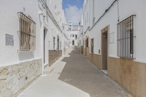 A narrow street with white buildings, barred windows, and a clear sky. - Apartment 'Isabel Casa Del Mar' with Wi-Fi (Conil de la Frontera)