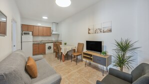Un espacio habitable compacto con kitchenette, comedor y zona de estar.