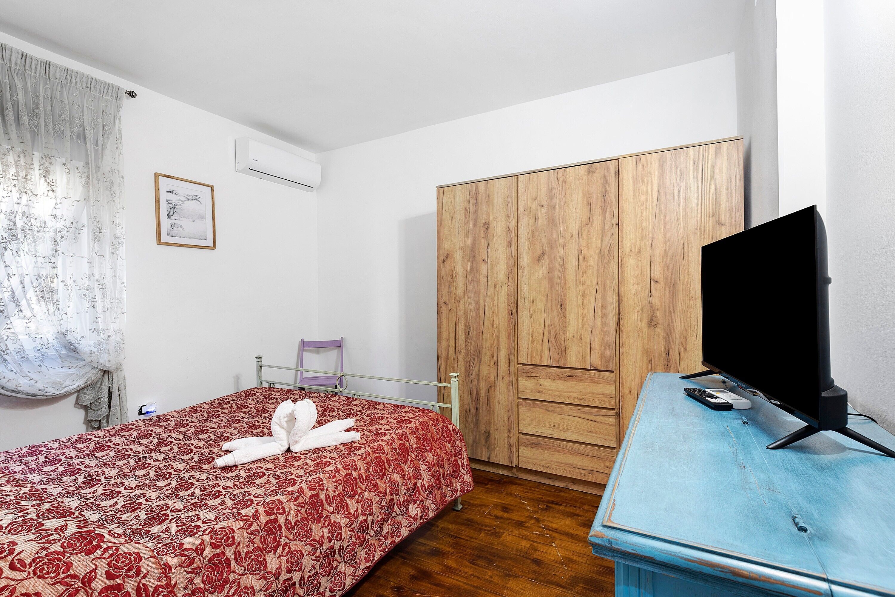 Una camera da letto con un letto, un armadio, una televisione e una scrivania.