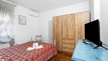 Una camera da letto con un letto, un armadio, una televisione e una scrivania.