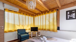 Een slaapkamer met een bed, een televisie, een stoel en gordijnen.