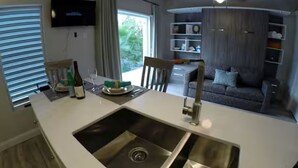 Een moderne keuken met een centraal eiland, een roestvrijstalen spoelbak en een flatscreen televisie aan de muur.