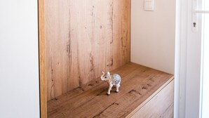 A wooden bench with a small elephant figurine, a round mirror, and a white door. - C Gato 7 Riscas - Recanto Da Oliveira (Obidos)