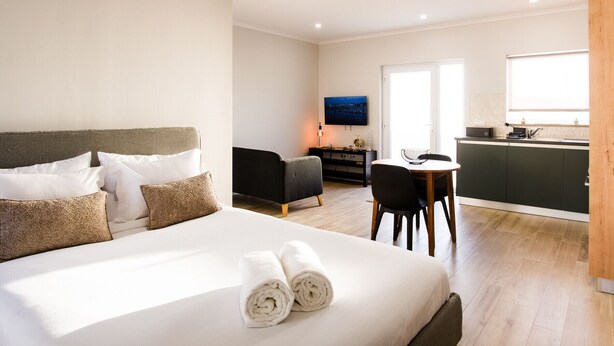 A hotel room with a bed, a desk, a chair, a television, and a kitchenette. - C Gato 7 Riscas - Recanto Da Oliveira (Obidos)