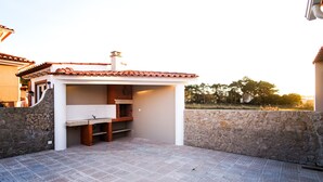 A patio area with a stone wall, a tiled floor, and a small structure with a tiled roof. - C Gato 7 Riscas - Recanto Da Oliveira (Obidos)