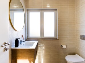 A bathroom with a sink, mirror, toilet, and a window. - C Gato 7 Riscas - Casa Maior (Obidos)