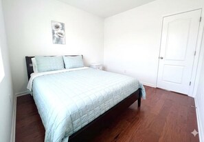 Ein Schlafzimmer mit einem Bett, einem Nachttisch, einer Tür und einem Wandbild.