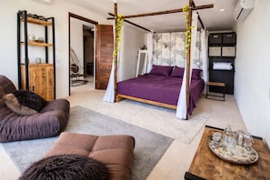 A bedroom with a four-poster bed, a sofa, a wooden cabinet, and a small table with glasses.