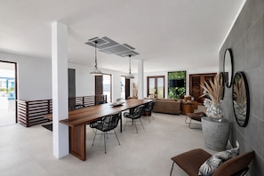 A spacious living area with a wooden dining table, black chairs, a sofa, and a large mirror.