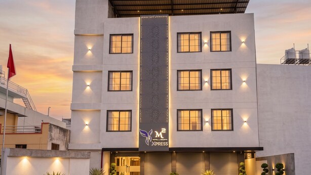Ein modernes Hotel mit einer zentralen, vertikalen Lichtleiste, zahlreichen Fenstern und einer geschlossenen Garagentür.