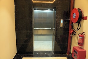 An elevator with a fire extinguisher mounted on the wall beside it.