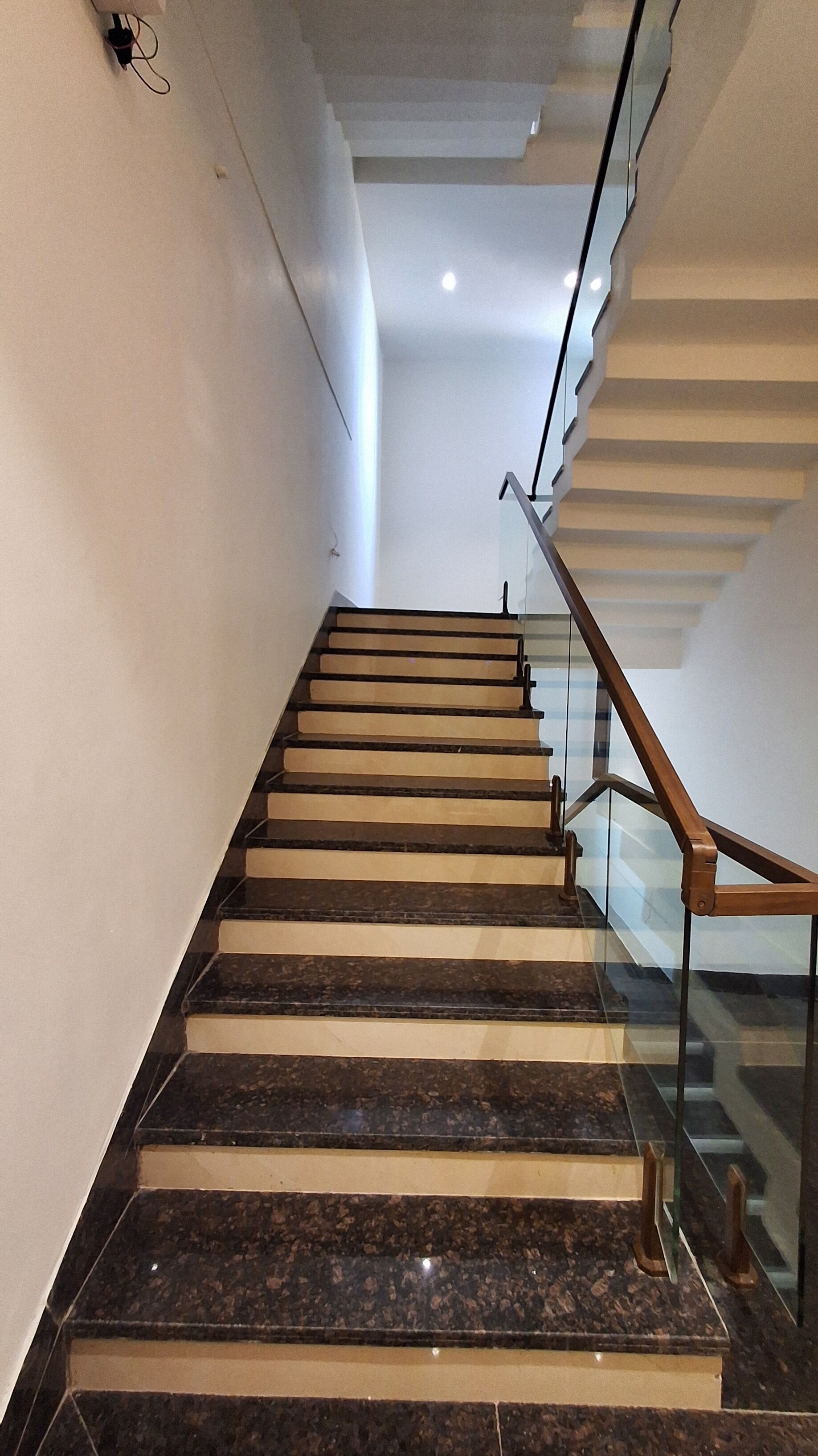 A staircase with marble steps and wooden handrails, leading upwards.