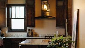 Une cuisine avec des meubles de rangement en bois, un îlot central, un luminaire suspendu et une fenêtre.
