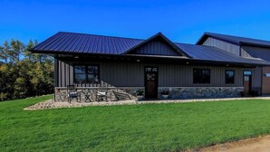 Un bâtiment moderne doté d’un toit en métal, de fondations en pierre et d’une pelouse bien entretenue.