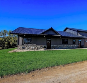 A modern building with a metal roof, a stone foundation, and a well-maintained lawn. - 3 bed 2 bath luxury home with river view private. (Hutchinson)