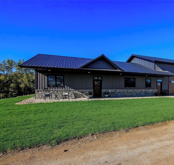 A modern building with a metal roof, a stone foundation, and a well-maintained lawn. - 3 bed 2 bath luxury home next to crow river private. (Hutchinson)