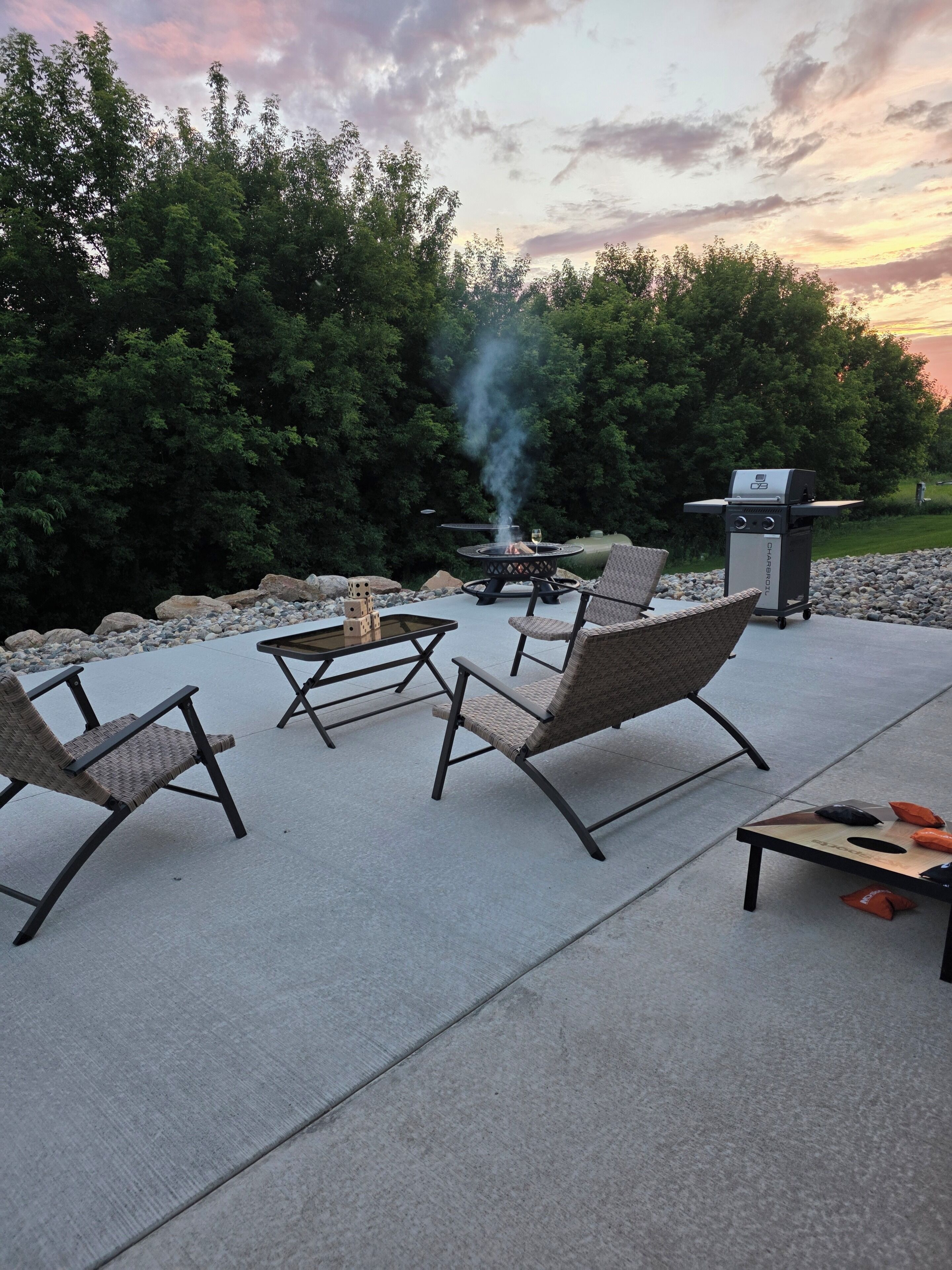 An outdoor patio with wicker chairs, a round table, and a grill.