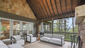 Ein überdachter Außenbereich mit Sofas und Tischen, einer Holzbeschichtung und Blick ins Freie.
