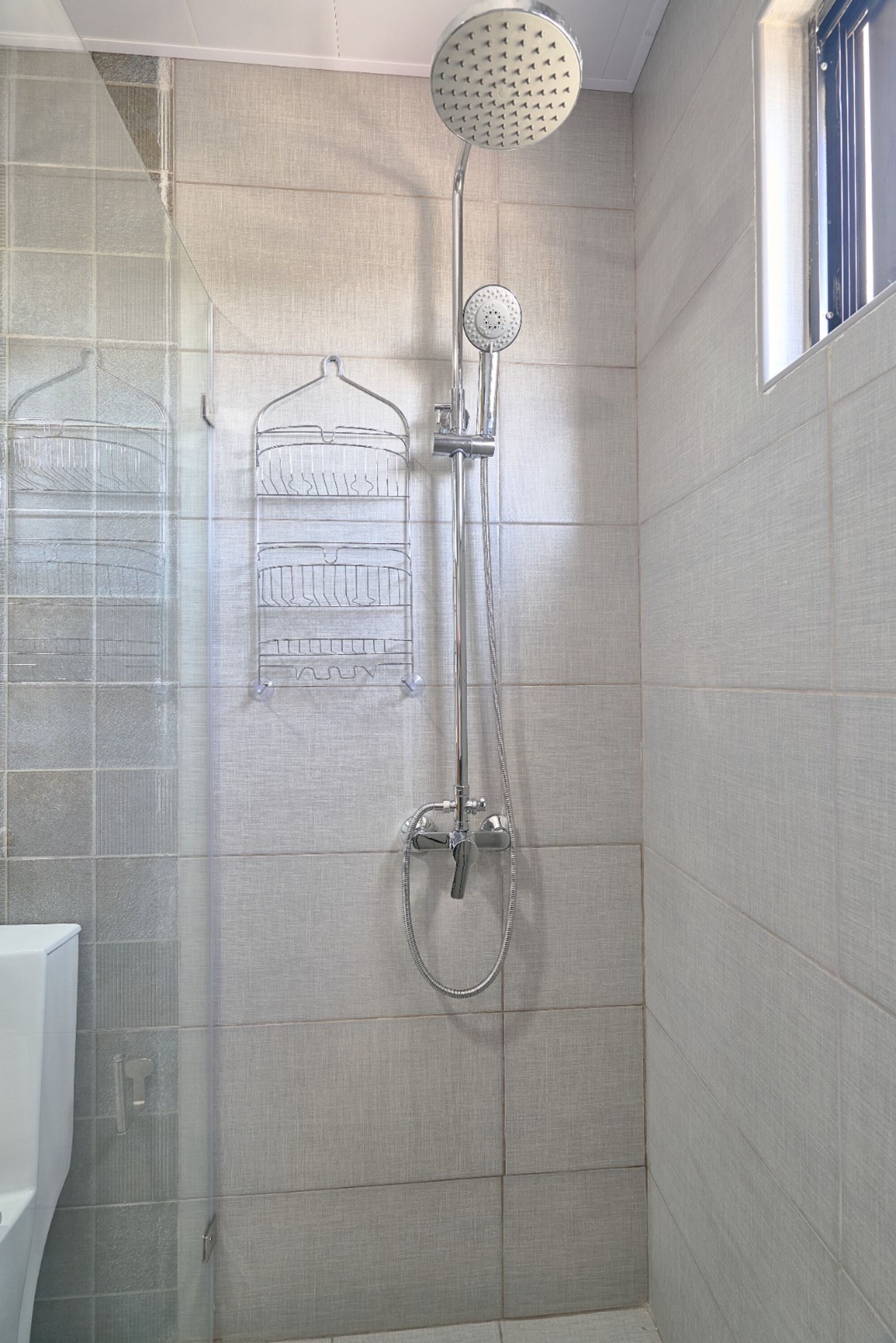 A shower with a handheld showerhead and a wall-mounted faucet.