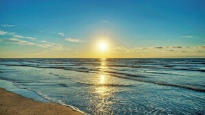 A beach with sunlight reflecting on the water. - Sunkissed Seaside by Avantstay Walk to Beach + Boardwalk Pool + Tennis + Basketball Access (Port Aransas)