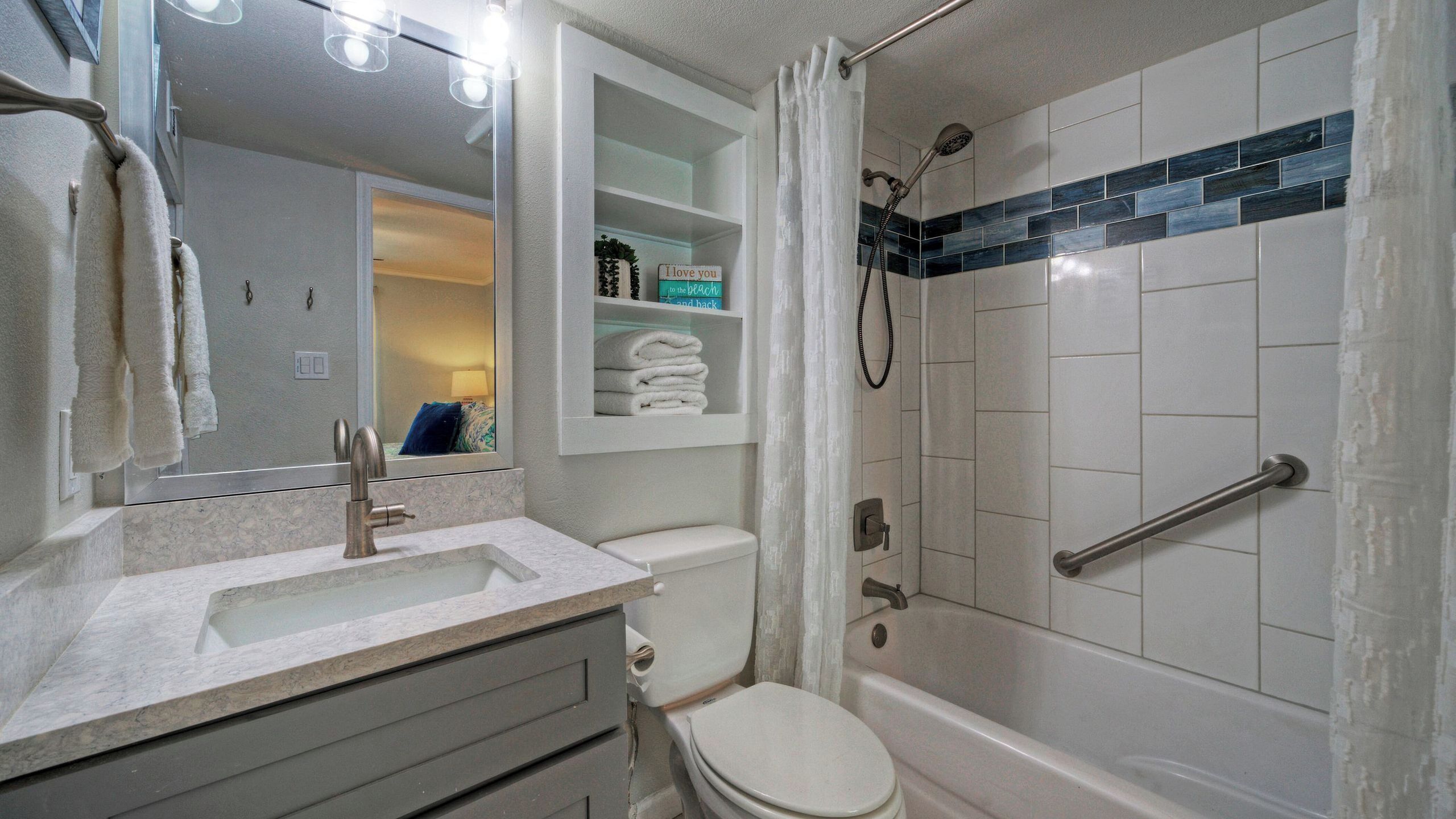 Een badkamer met een wastafel, toilet, douche en spiegel.