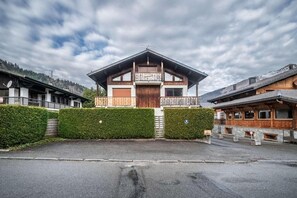 A chalet-style building with a balcony, a garage, and a paved driveway. - Ground floor, terrace, parking, tv, ski locker, 50m², Morzine (Morzine)