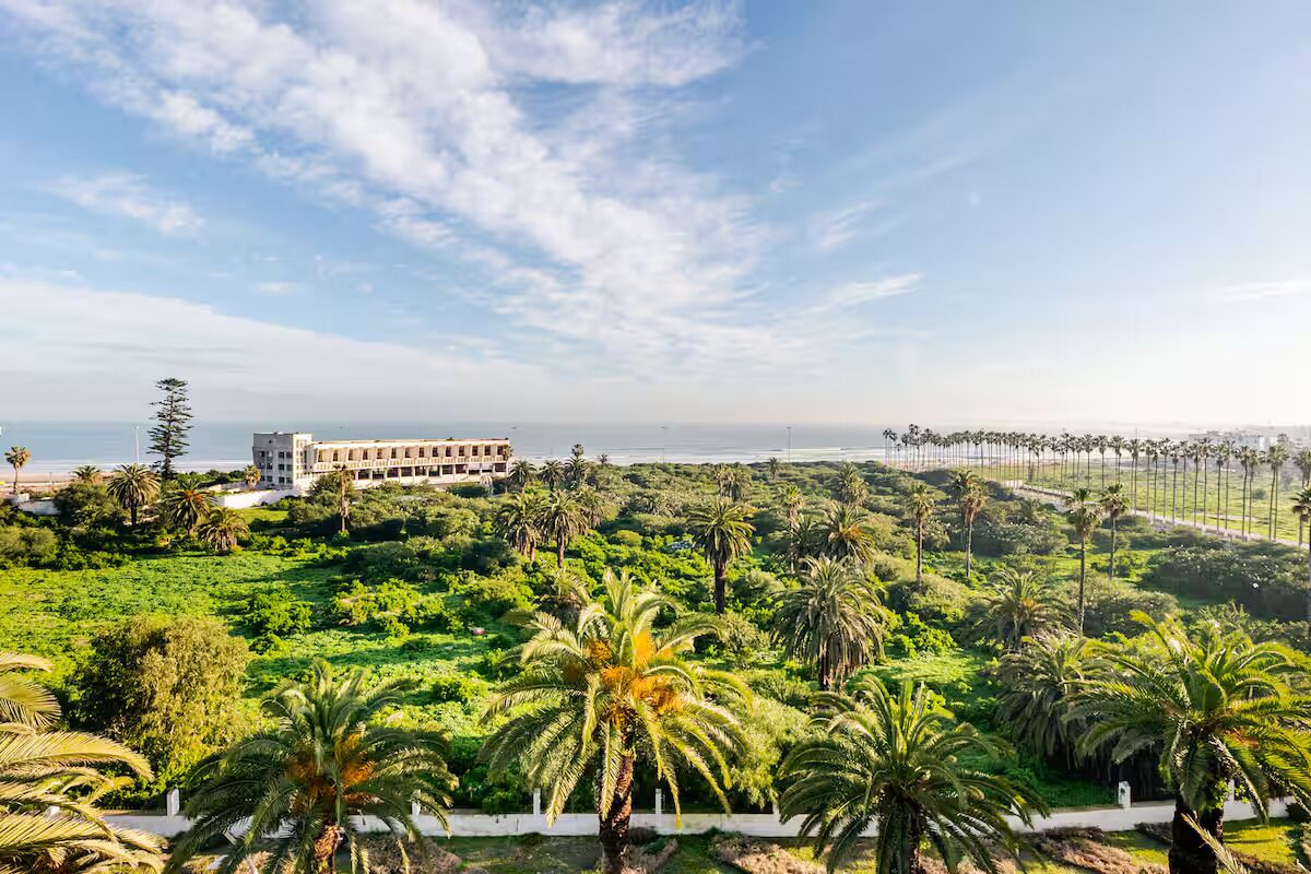 A hotel with a view of the ocean, surrounded by lush greenery and palm trees.
