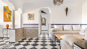 A hotel lobby with a checkered floor, a white sofa, a patterned tile wall, and a painting. - Lovely 2-El Jadida City Center Apt – Ideal Spot, Beach View & WiFi (El Jadida)