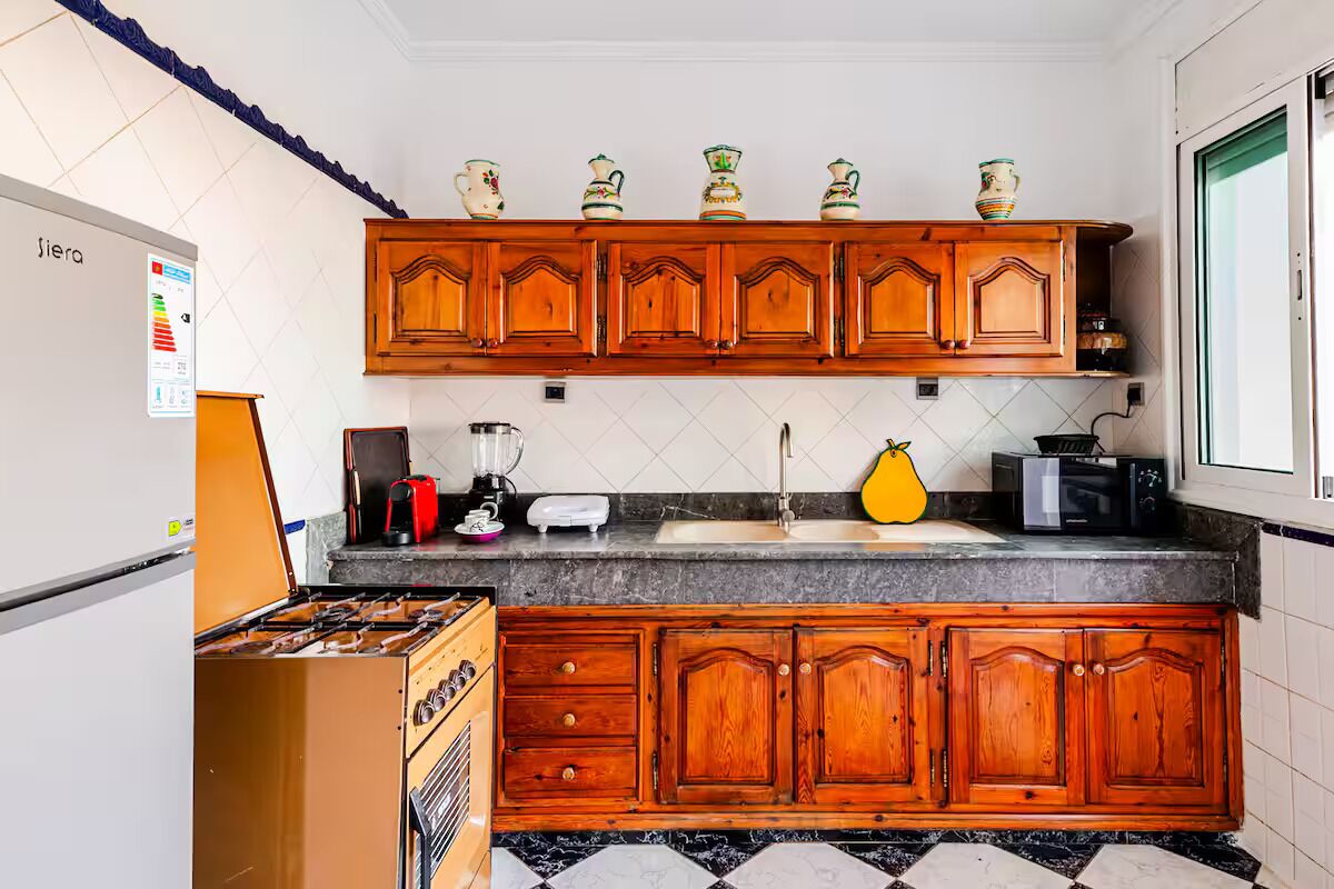 Cozinha com armários de madeira, fogão a gás, pia e diversos eletrodomésticos.