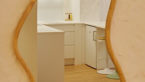 Uma cozinha moderna com armários brancos, piso de madeira e espelho com moldura oval.